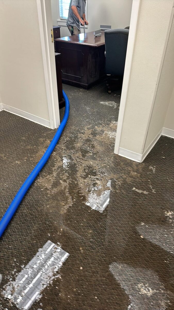 Office carpet mid-job with cleaning hose run into a private office, from a Duval Floor Care Facebook job photo